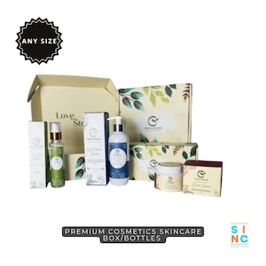Puede incluir: Una colecci&oacute;n de productos para el cuidado de la piel, que incluye botellas, frascos y cajas, dispuestos sobre una superficie blanca. Los productos presentan una combinaci&oacute;n de colores verde y blanco con dise&ntilde;os bot&aacute;nicos. El texto "PREMIUM COSMETICS SKINCARE BOX/BOTTLES" es visible.