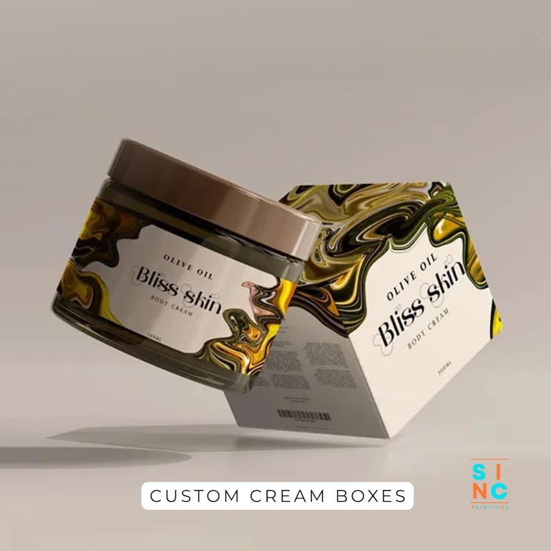 Puede incluir: Un tarro de cristal y una caja de crema corporal Bliss Skin. El tarro tiene una tapa marr&oacute;n y una etiqueta con el texto "Olive Oil Bliss Skin Body Cream". La caja tiene un dise&ntilde;o similar con el mismo texto y un patr&oacute;n de remolino amarillo y negro. El texto "Custom Cream Boxes" est&aacute; en la parte inferior.