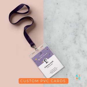 Könnte beinhalten: Ein klarer Ausweishalter aus Kunststoff mit einem lila Schlüsselband und einem silbernen Verschluss. Die Karte zeigt den Namen "Catherine Smith, Grafikdesigner" und Kontaktinformationen. Der Text "CUSTOM PVC CARDS" befindet sich in einem orangefarbenen Rechteck.