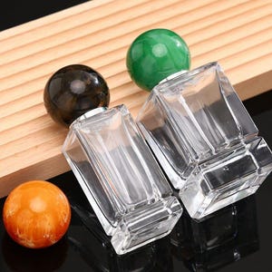 May include: A white ceramic mug with a black handle and the text "But First, Coffee" in a bold, black font. The mug is sitting on a wooden surface. The mug is approximately 4 inches tall.