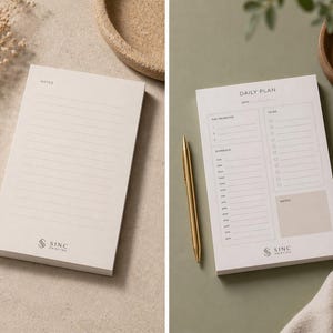 May include: Two beige notepads with gold pens. One notepad has lined pages and the word "NOTES" at the top. The other notepad has a "DAILY PLAN" layout with sections for priorities, schedule, and to-do lists. Both notepads have the "SINC PRINTING" logo.