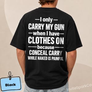 Può includere: Una t-shirt nera a maniche corte con testo bianco sul retro che recita: I only CARRY MY GUN when I have CLOTHES ON because CONCEAL CARRY WHILE NAKED IS PAINFUL. La maglietta presenta un girocollo e una vestibilità standard, vista dal retro.