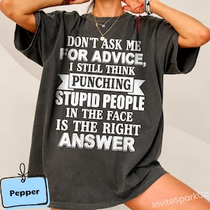 Könnte beinhalten: Ein anthrazitfarbenes Kurzarm-T-Shirt mit weißem, abgenutztem Text, der lautet: DON'T ASK ME FOR ADVICE, I STILL THINK PUNCHING STUPID PEOPLE IN THE FACE IS THE RIGHT ANSWER. Das T-Shirt hat eine lockere Passform und eine verwaschene Vintage-Optik.