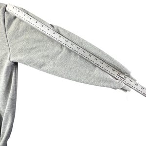 Puede incluir: Una manga de sudadera gris claro se mide con una regla. La manga est&aacute; hecha de una tela suave y texturizada. La regla muestra una medida de aproximadamente 56 cm desde la costura del hombro hasta el pu&ntilde;o.