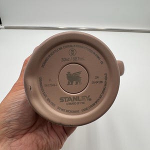 Pu&ograve; includere: Fondo del bicchiere Stanley marrone chiaro. Il fondo del bicchiere riporta la scritta "30oz/887ml" e "Dishwasher Safe BPA Free". Il logo Stanley &egrave; al centro del fondo del bicchiere.
