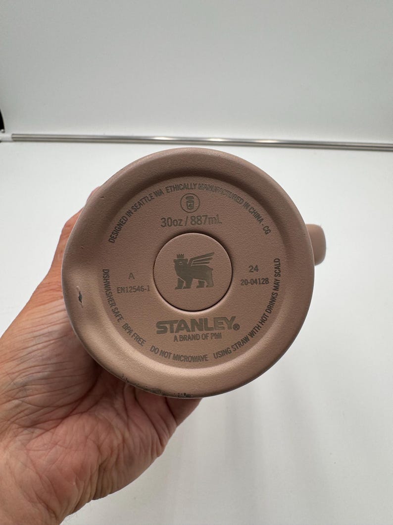 Pu&ograve; includere: Fondo del bicchiere Stanley marrone chiaro. Il fondo del bicchiere riporta la scritta "30oz/887ml" e "Dishwasher Safe BPA Free". Il logo Stanley &egrave; al centro del fondo del bicchiere.