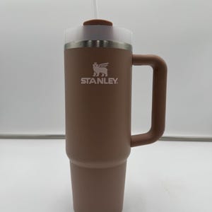 Pu&ograve; includere: Un bicchiere Stanley marrone con manico, coperchio trasparente e cannuccia. Il logo Stanley &egrave; stampato in bianco. Questo bicchiere isolato &egrave; progettato per mantenere le bevande calde o fredde per ore. Capacit&agrave; di circa 0,7 litri.