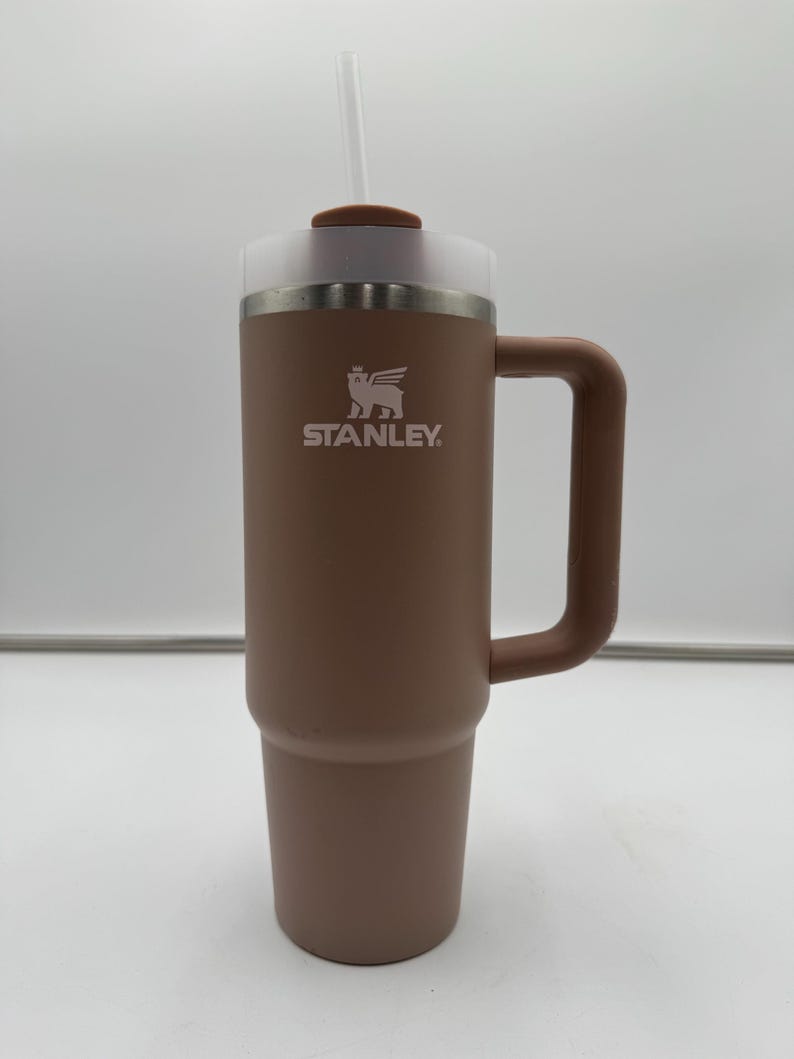 Pu&ograve; includere: Un bicchiere Stanley marrone con manico, coperchio trasparente e cannuccia. Il logo Stanley &egrave; stampato in bianco. Questo bicchiere isolato &egrave; progettato per mantenere le bevande calde o fredde per ore. Capacit&agrave; di circa 0,7 litri.