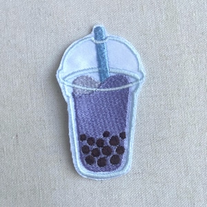 May include: Purple embroidered iron-on patch of a boba tea cup with a blue straw and black boba pearls.