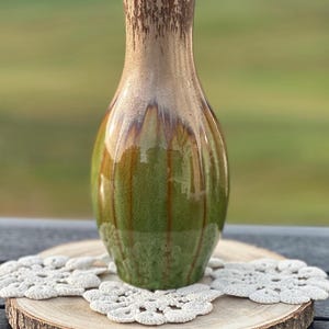 May include: A tall, slender ceramic vase featuring a glossy finish with a gradient color transition from a light beige at the narrow neck to a deep, vibrant green at the base, accented by vertical brown drip patterns and a subtle crackle texture.