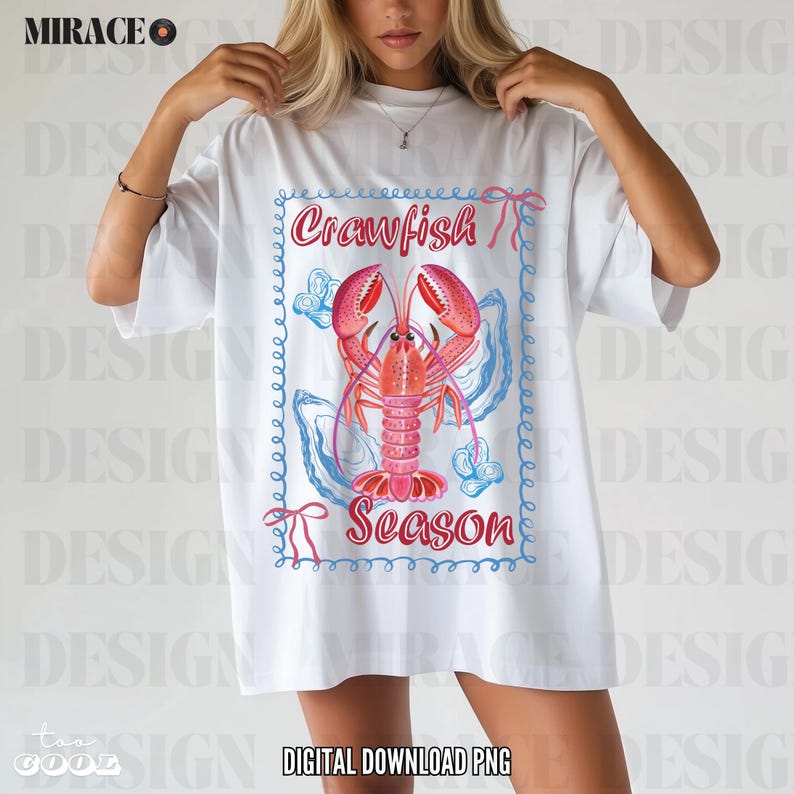 Op de afbeelding: Wit T-shirt met een afbeelding van een rode kreeft in een blauwe en roze schelp met de tekst "Crawfish Season" in een blauwe en roze rand.