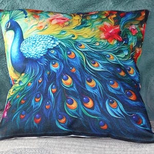 May include: Square decorative pillow featuring a vibrant peacock design. The pillow showcases a blue peacock with a detailed tail, set against a colorful floral background with red, yellow, and green accents. The pillow has a black border.