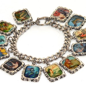 May include: A silver charm bracelet with 12 charms featuring images of mermaids in various poses. The charms are attached to a silver chain with a lobster clasp.