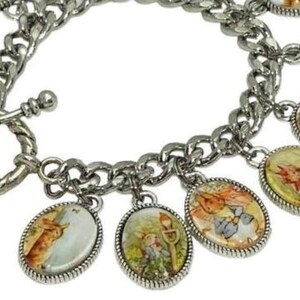 May include: A silver-toned chain link charm bracelet featuring multiple oval-shaped pendants. Each pendant displays a colorful illustration of a rabbit character in various outdoor settings. The bracelet is secured with a circular toggle clasp.