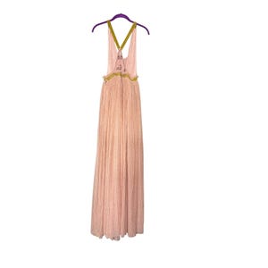 May include: A floor-length, light pink dress with a pleated design. The dress features a halter-style top with olive green straps and decorative accents. It hangs on a purple hanger.
