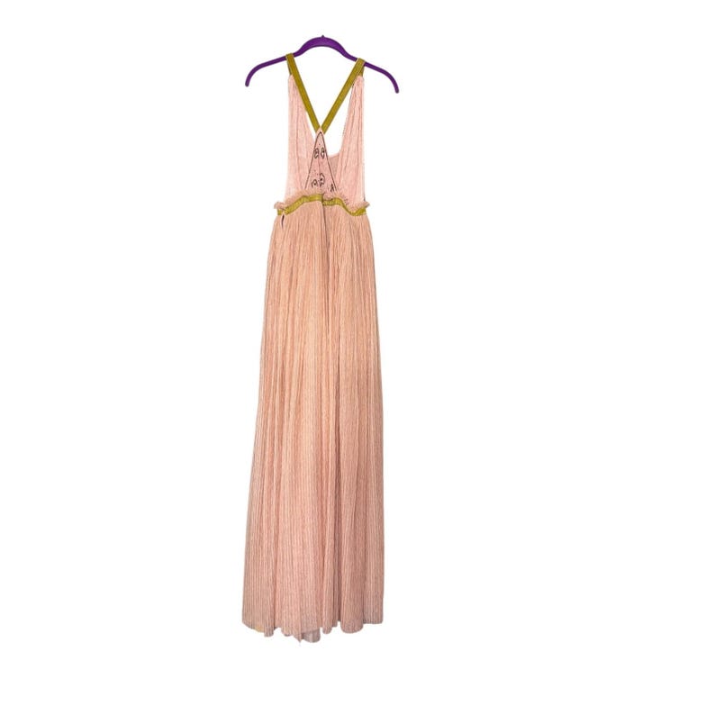 May include: A floor-length, light pink dress with a pleated design. The dress features a halter-style top with olive green straps and decorative accents. It hangs on a purple hanger.
