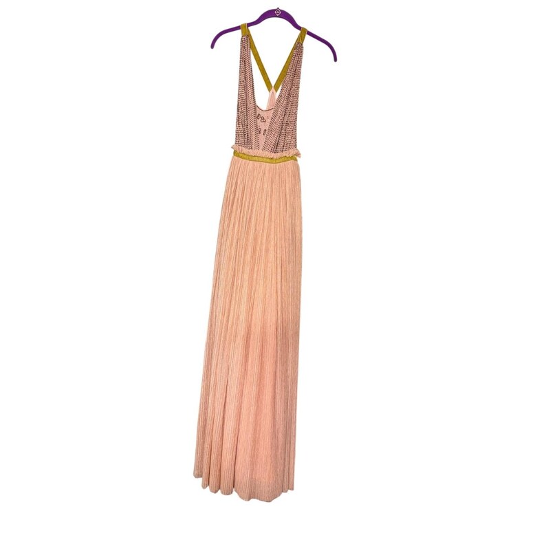 May include: A floor-length peach-colored dress with a halter top, hanging on a purple hanger. The top of the dress has a patterned design, with a gold-colored band at the waist. The skirt is pleated.
