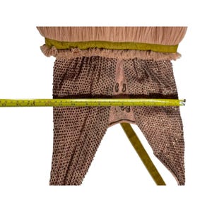 May include: A vintage, blush-colored garment with intricate beadwork and a pleated top. The garment features a gold ribbon and measures approximately 15 inches in length. The design includes decorative embroidery.