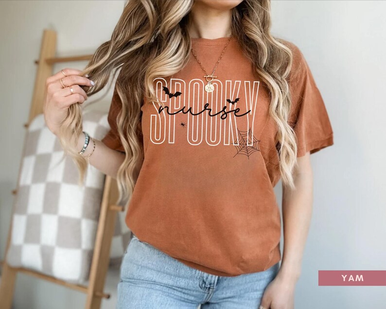 Puede incluir: Camiseta color &oacute;xido con la frase "SPOOKY nurse" en blanco, con murci&eacute;lagos y telara&ntilde;as. Esta camiseta de estilo casual es perfecta para Halloween o como regalo para una enfermera. Se combina con vaqueros azules.