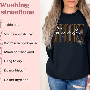 Puede incluir: Sudadera negra de manga larga con las palabras "Spooky Nurse" en naranja y blanco, con murci&eacute;lagos y un dise&ntilde;o de telara&ntilde;a. Tambi&eacute;n se muestran las instrucciones de lavado.