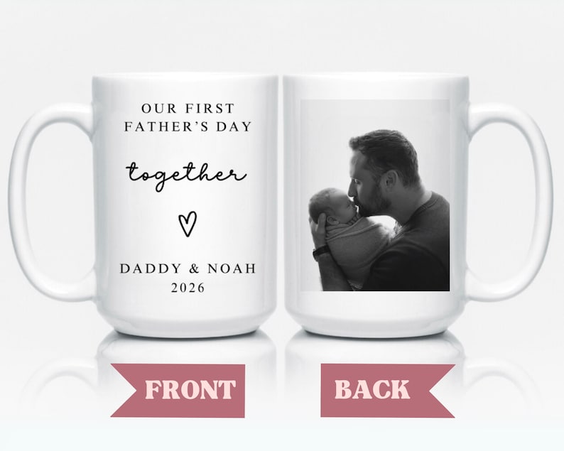 May include: White ceramic mug with the text "OUR FIRST FATHER'S DAY together" and "DADDY & NOAH 2026" on one side. The other side features a black and white photo of a father kissing a baby. A heart symbol is also present.