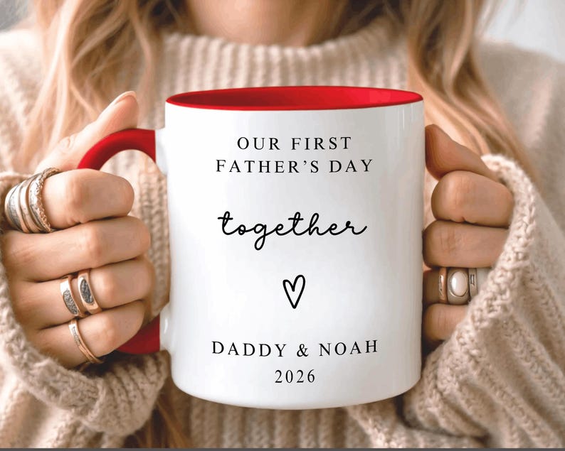 May include: White ceramic mug with a red interior and handle. The mug features the text "OUR FIRST FATHER'S DAY together" with a heart symbol and the names "DADDY & NOAH" and the year "2026".