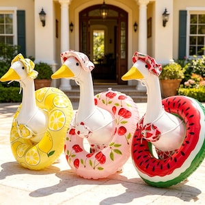 May include: Three inflatable goose pool floats. One has a yellow lemon design, another has a pink cherry design, and the third has a red watermelon design. Each goose wears a matching hat and swimsuit.