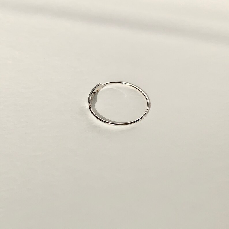 May include: A simple silver ring with a flat band.