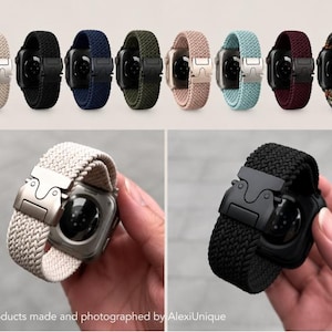 May include: A collection of Apple Watch bands in various colors, including beige, black, navy blue, olive green, and burgundy. The bands feature a woven design and a metal clasp. The bottom of the image shows a close-up of a beige and black band.