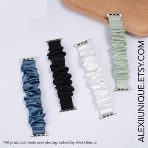 May include: Four Apple Watch bands in blue, black, white, and pale green. Each band has a pleated, ruched design and silver-colored connectors. The bands are displayed on a white surface with the text ALEXIUNIQUE.ETSY.COM.
