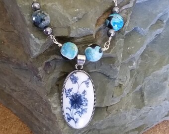 White ceramic with blue floral print pendent on beaded necklace, Verigated blue beaded necklace wth white and blue pendent