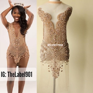 May include: A gold beaded and sequined dress applique with a sheer mesh backing. The applique features a deep V-neckline and a flowing, cascading design. The text "@LynnTrims" is visible on the applique.