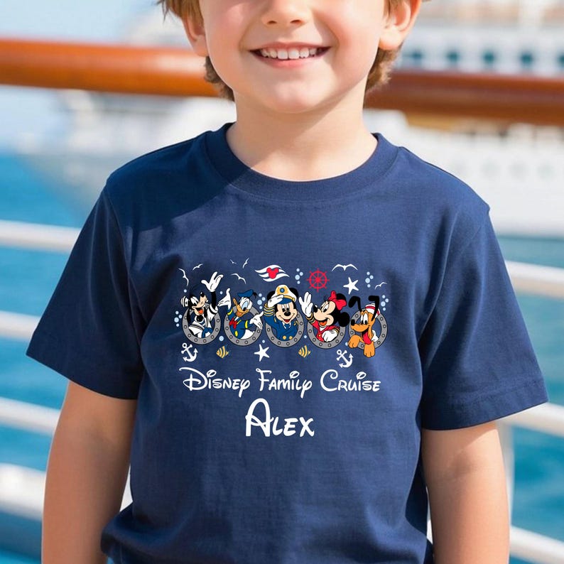 May include: Navy blue t-shirt featuring Disney characters in porthole designs. The shirt includes the text "Disney Family Cruise" and the name "Alex" in white. The design includes Mickey Mouse, Donald Duck, Goofy, and Pluto.