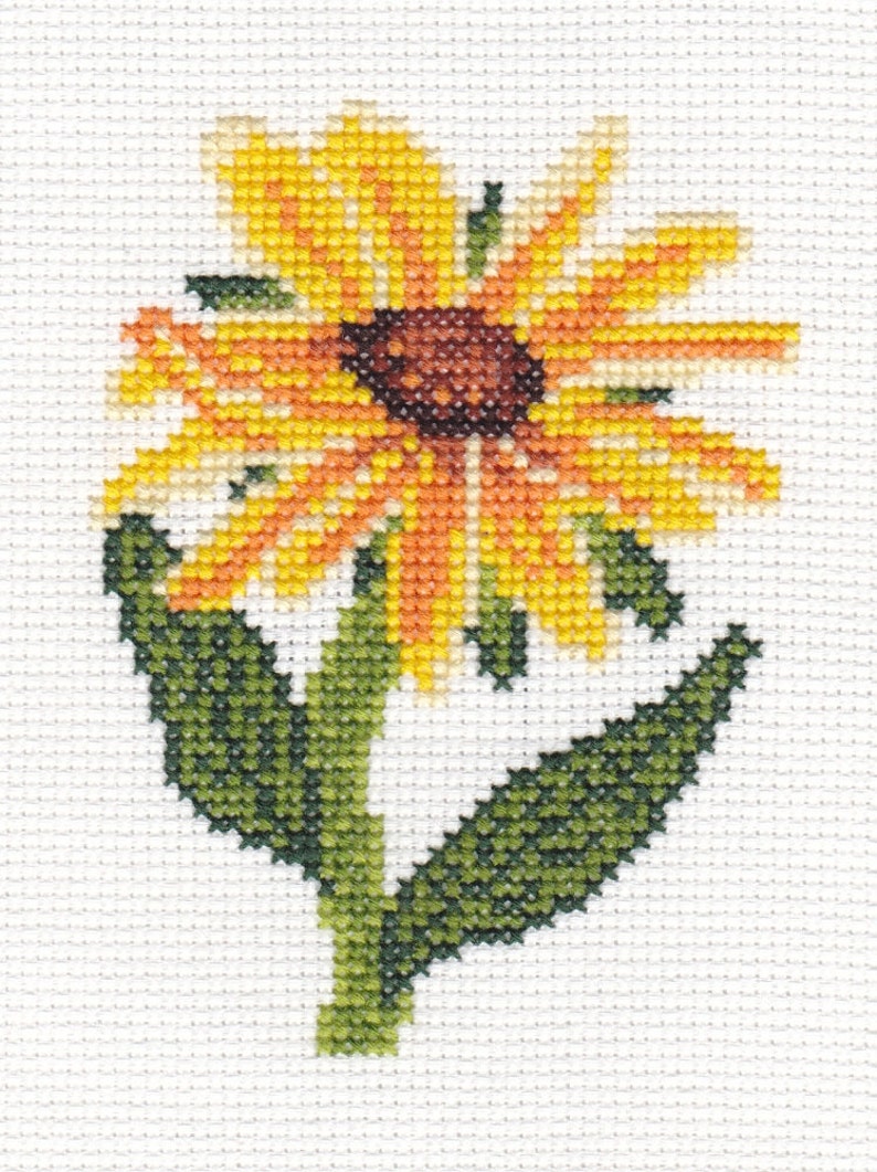 K&ouml;nnte beinhalten: Eine Kreuzstich-Stickerei einer gelben und orangefarbenen Blume mit gr&uuml;nen Bl&auml;ttern. Die Blume hat eine braune Mitte.