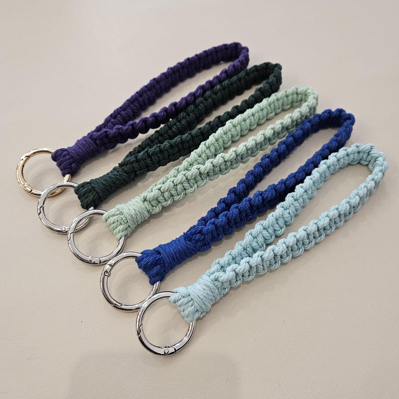 Pu&ograve; includere: Cinque portachiavi da polso in macram&egrave; di vari colori: viola, verde scuro, verde chiaro, blu e azzurro. Ogni portachiavi presenta un anello intrecciato e un anello in metallo argentato o dorato.