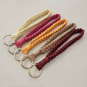 Pu&ograve; includere: Una collezione di sei portachiavi da polso in macram&egrave; in vari colori. I portachiavi presentano un design intrecciato e sono nelle tonalit&agrave; di beige, rosa, arancione, marrone chiaro e bordeaux. Ogni portachiavi ha un anello in metallo color argento.