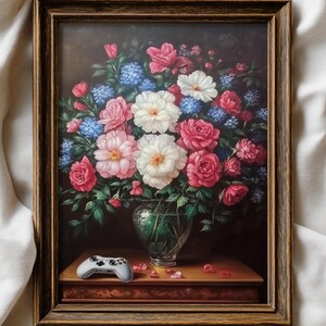 May include: Framed floral still life painting featuring a bouquet of pink, white, and blue flowers in a glass vase. A white and gray video game controller rests on a wooden table in front of the vase. The frame is brown.