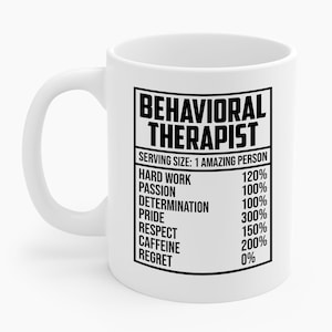May include: White ceramic mug with a black rectangular graphic that reads "BEHAVIORAL THERAPIST." Below the text is a list of qualities and percentages, including "Hard Work" at 120% and "Caffeine" at 200%.