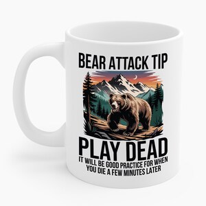 Puede incluir: Taza de cerámica blanca con una ilustración de un oso marrón y el texto "BEAR ATTACK TIP PLAY DEAD IT WILL BE GOOD PRACTICE FOR WHEN YOU DIE A FEW MINUTES LATER".