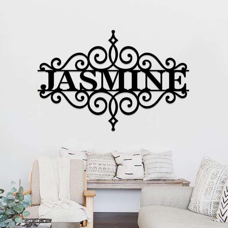 Pu&ograve; includere: Decorazione da parete in metallo nero con un design a volute decorative e il nome "JASMINE" al centro.