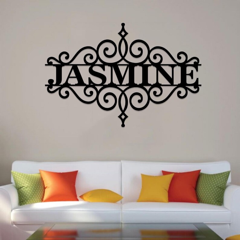 Pu&ograve; includere: Decorazione da parete in metallo nero con un design a volute decorative e il nome "JASMINE" al centro.