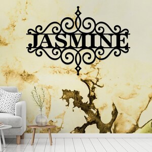 Pu&ograve; includere: Decorazione da parete in metallo nero con un design a volute decorative e il nome "JASMINE" al centro.