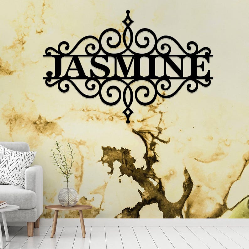 Pu&ograve; includere: Decorazione da parete in metallo nero con un design a volute decorative e il nome "JASMINE" al centro.