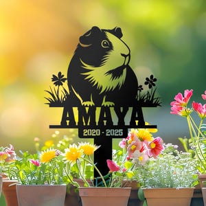 Puede incluir: Estaca de jardín conmemorativa de metal negro con una silueta de conejillo de indias y el nombre Amaya y las fechas 2020-2025.