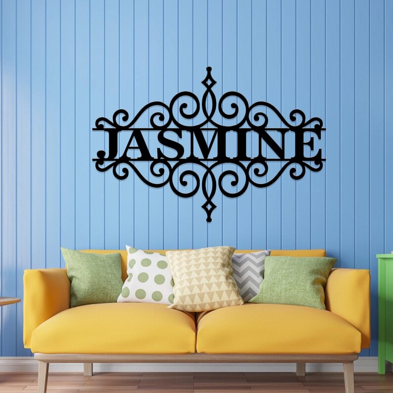 Pu&ograve; includere: Decorazione da parete in metallo nero con un design a volute decorative e il nome "JASMINE" al centro.