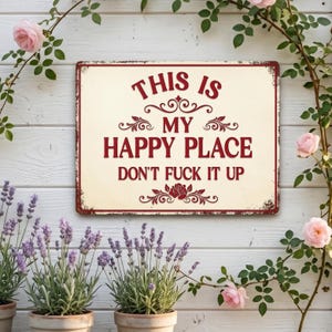 May include: A rectangular metal sign with a cream background and burgundy text that reads "THIS IS MY HAPPY PLACE DON'T FUCK IT UP." The sign has a distressed, vintage look and is surrounded by flowers and plants.