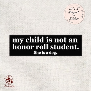 May include: A black rectangular magnet or sticker with the text "my child is not an honor roll student. She is a dog." The magnet measures 10 inches by 3 inches.