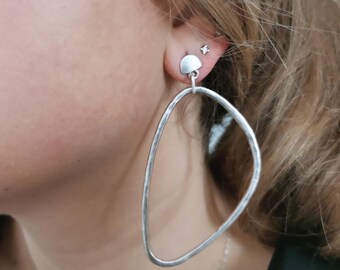 Puede incluir: Pendientes de plata con forma ovalada irregular grande. Los pendientes tienen un pequeño disco redondo en la parte superior.