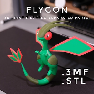 Puede incluir: Una figura de Flygon impresa en 3D, verde y marrón, con detalles rojos. La figura tiene grandes alas verdes con bordes rojos y una larga cola. El texto "FLYGON" y "3D PRINT FILE (PRE-SEPARATED PARTS)" se muestran. También se ven los tipos de archivo .3MF y .STL.