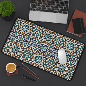 May include: A rectangular desk mat with a geometric pattern in shades of blue, teal, and brown. The mat features a black border and is designed to accommodate a mouse and keyboard. A white mouse is on the mat.